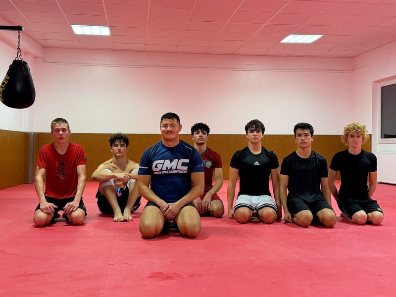 MMA-Gruppe kniet auf der Matte im MMA-Raum